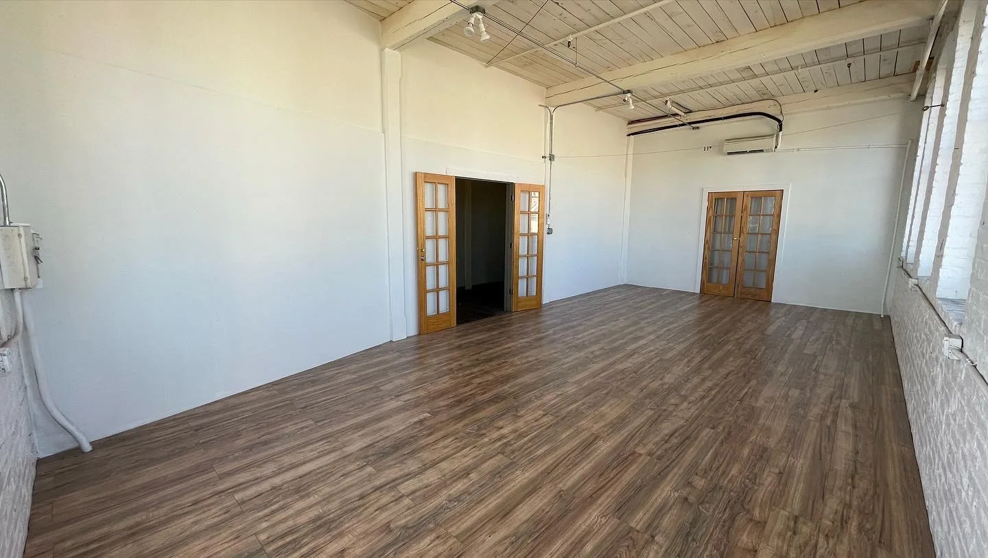 Open studio room with wood-plank ceiling, French doors and exposed brick