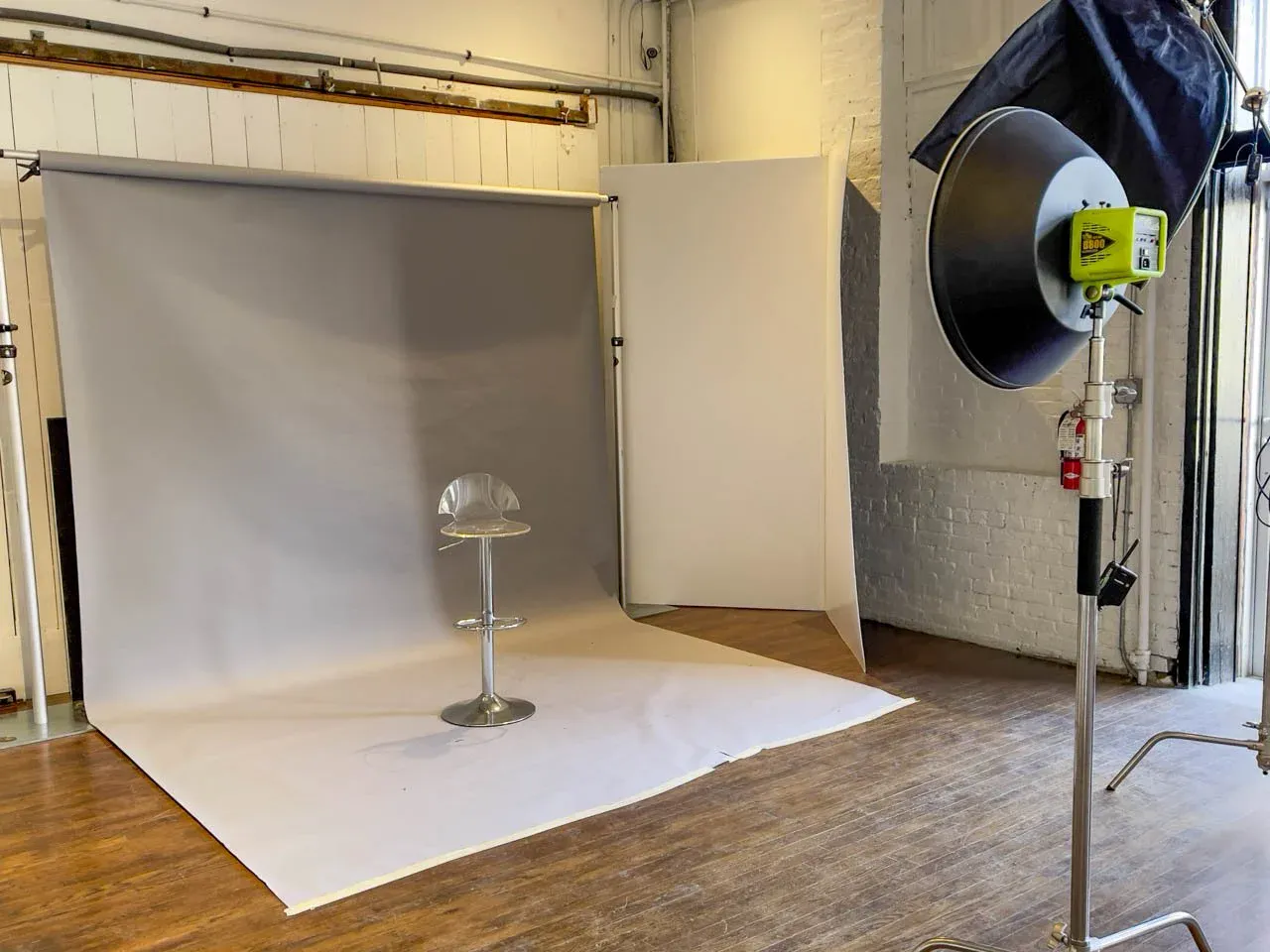 Studio corner set up for photography with a gray seamless backdrop and daylight from the door