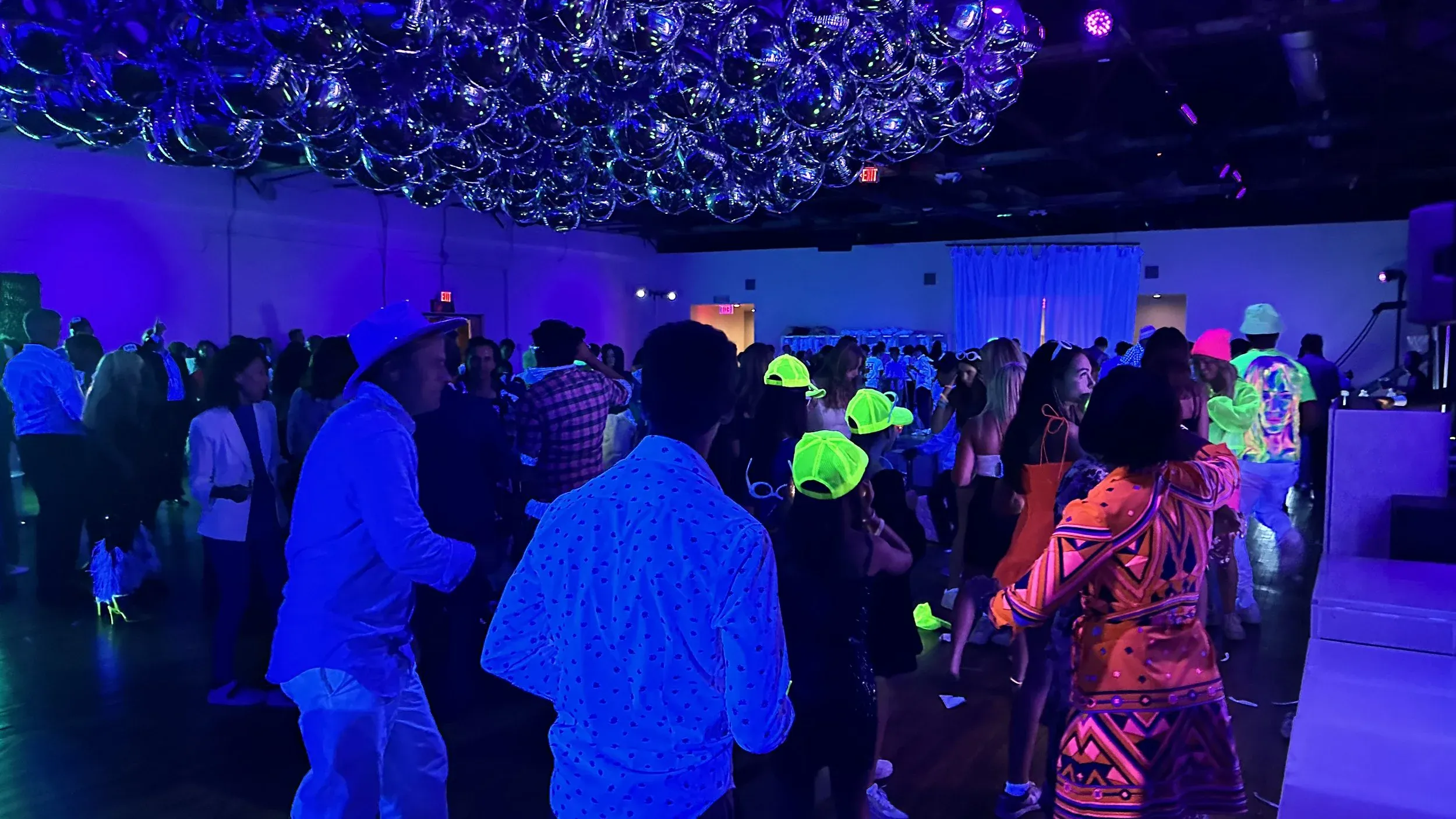 Blacklight dance floor packed with guests in glowing neon party gear