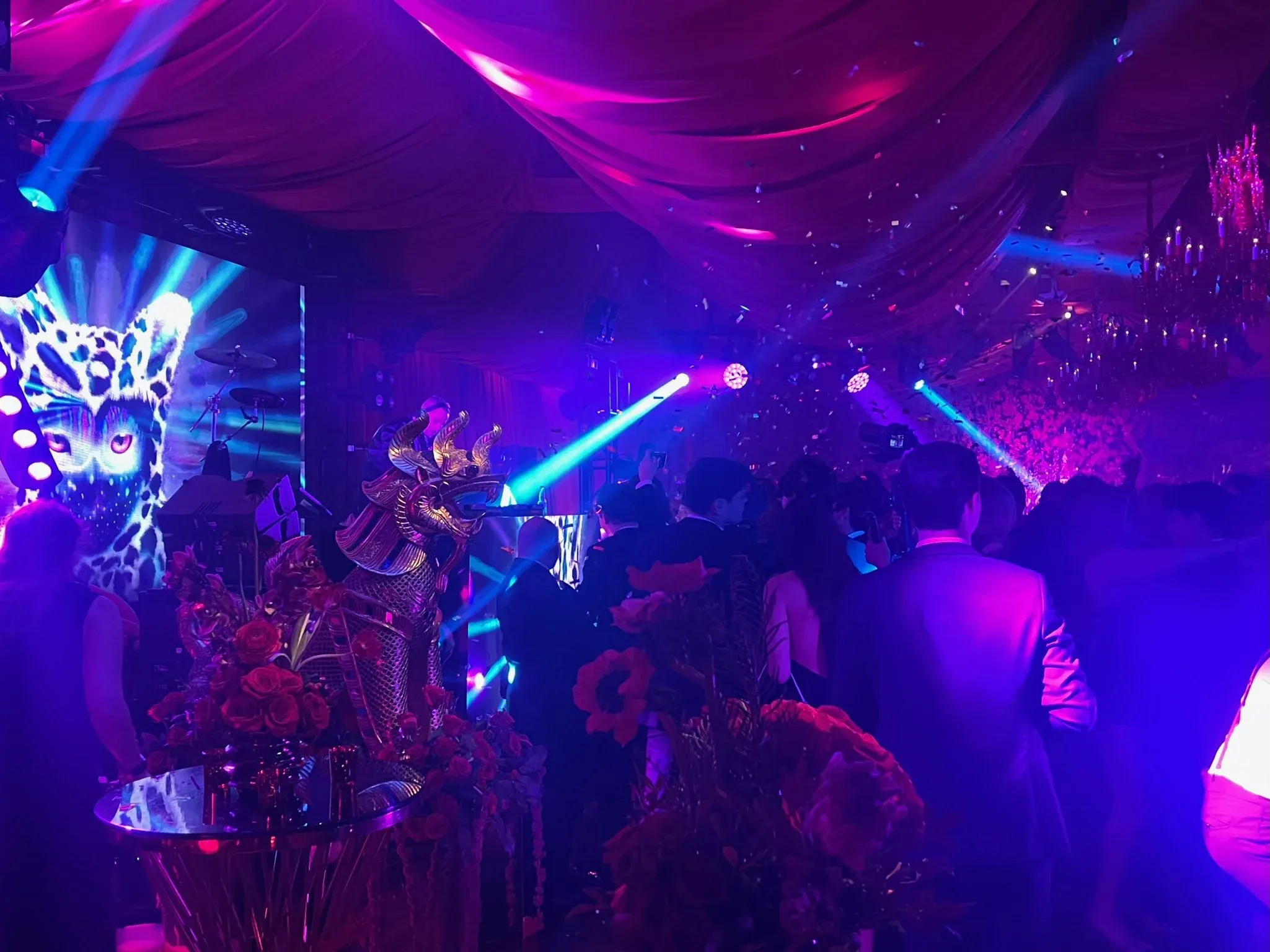 Confetti falling over a packed dance floor in blue and purple light