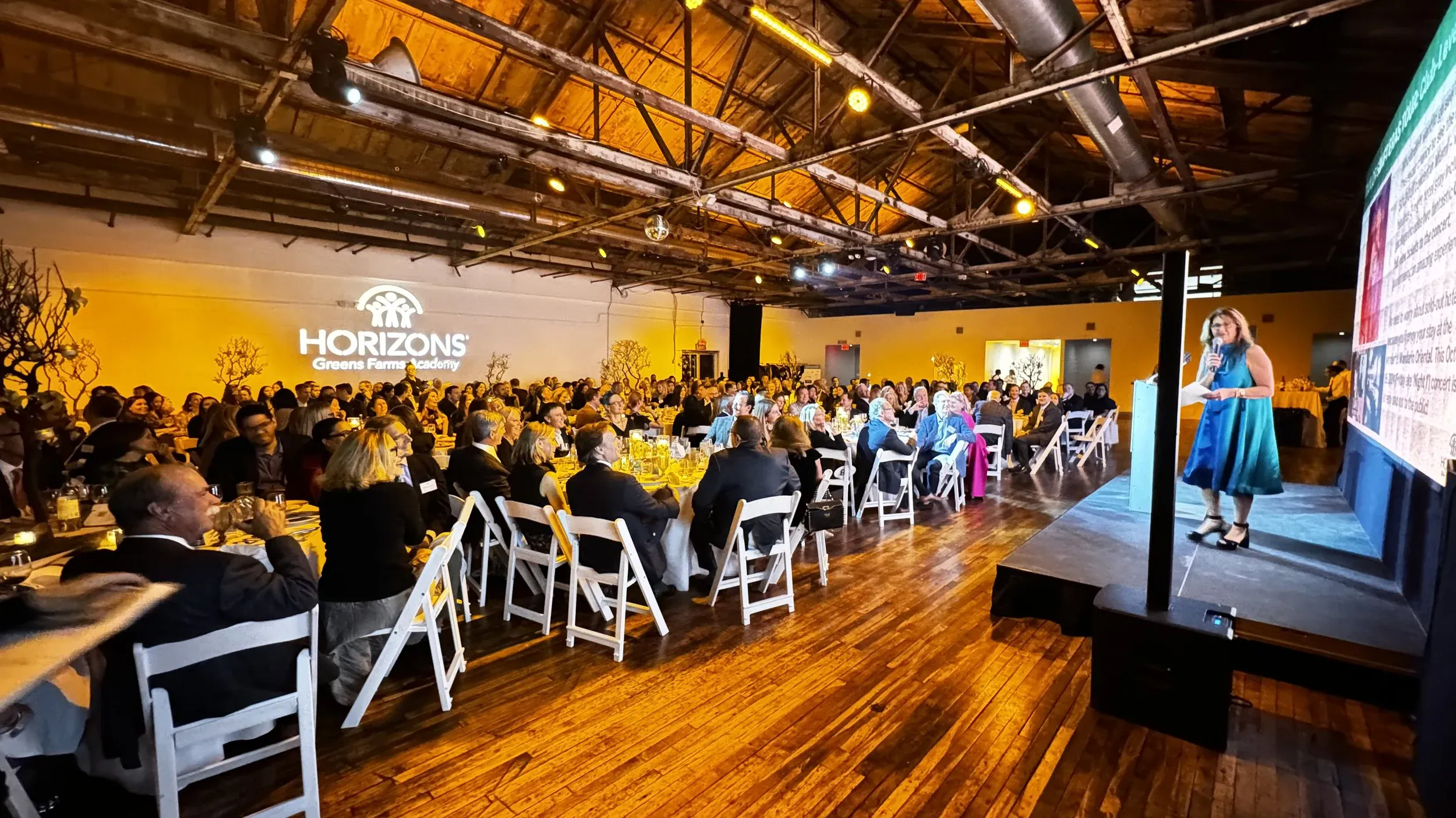Presenter addressing a seated conference luncheon at round tables