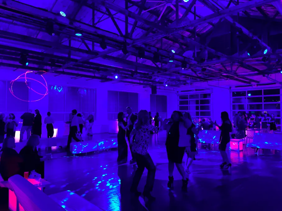 Guests dancing on a blue-lit dance floor with disco-ball reflections