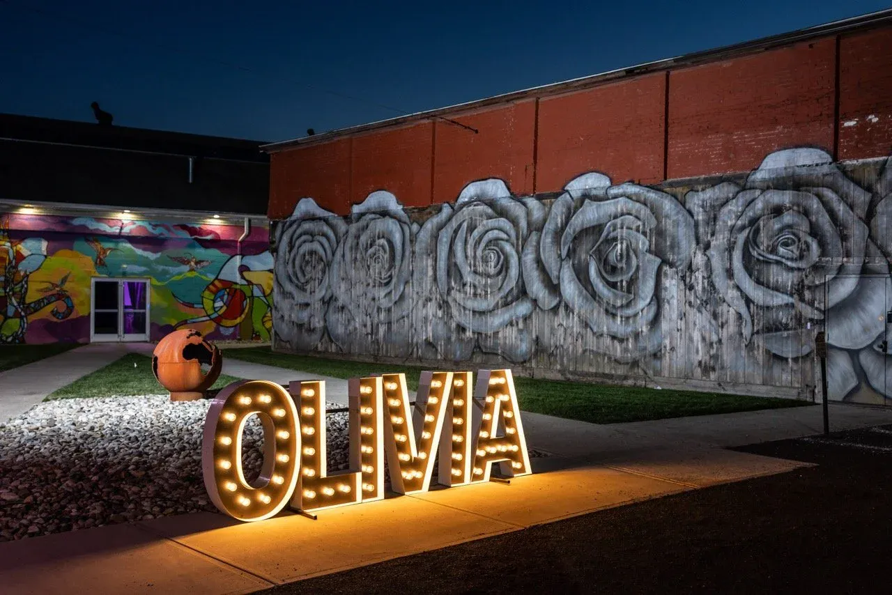 Light-up marquee letters at dusk against the rose mural in the courtyard