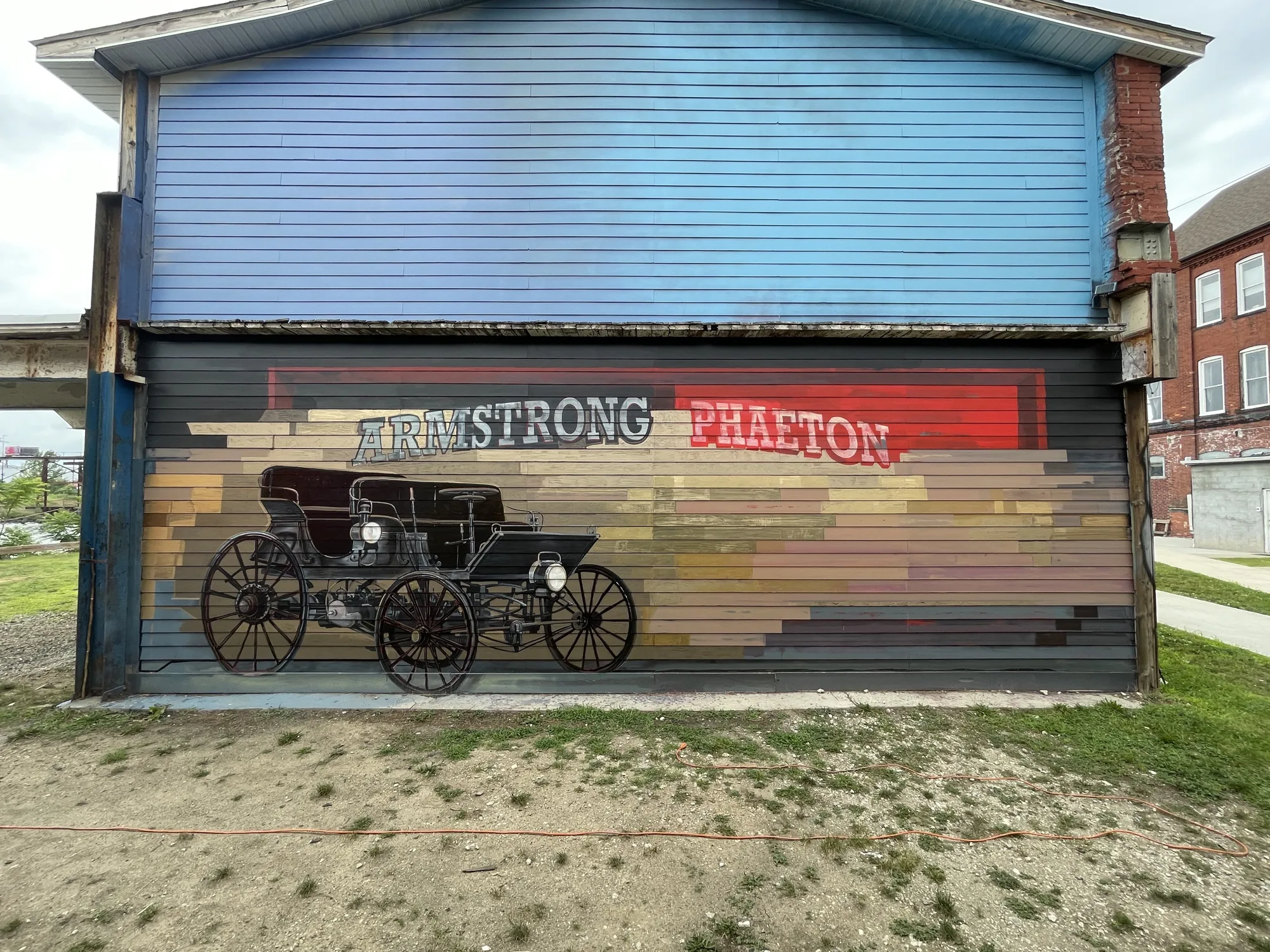 The Armstrong Phaeton mural by Brad Noble: a black vintage phaeton carriage with hand-painted Armstrong Phaeton lettering on the Armstrong building