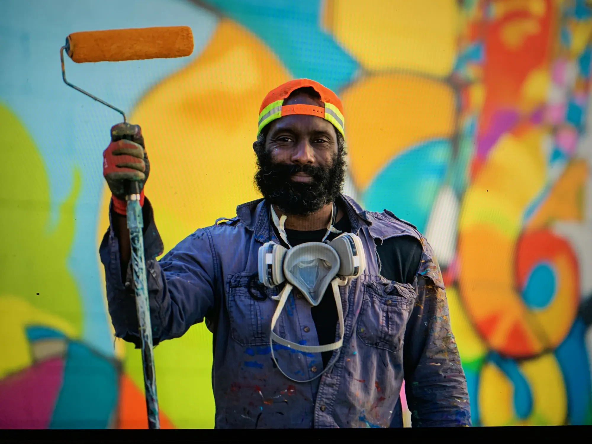 Craig Anthony Miller holds a paint roller in front of the Elephants mural at The Knowlton in Bridgeport, CT.