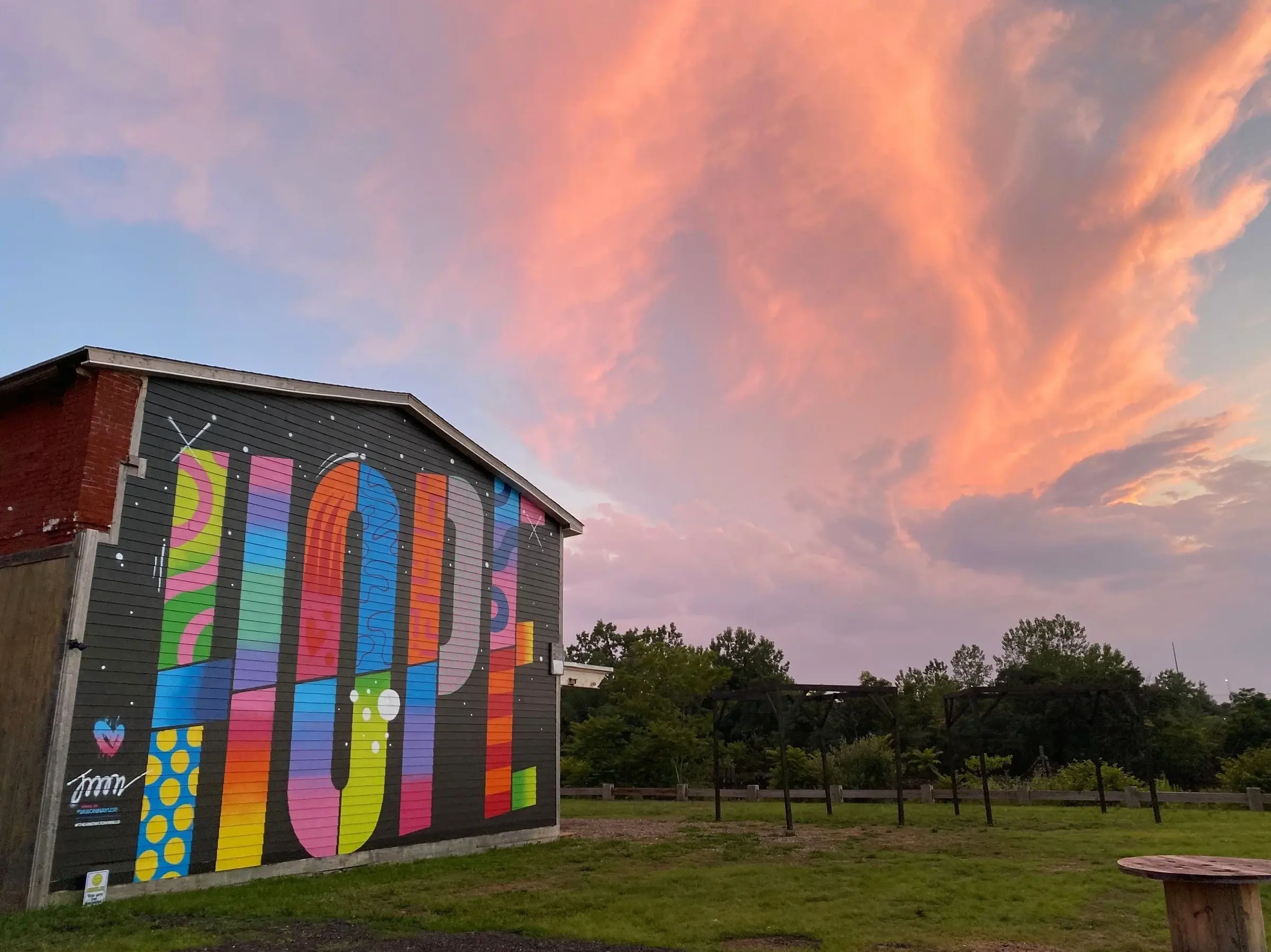 Jason Naylor's HOPE mural beneath a dramatic pink sunset sky at The Knowlton in Bridgeport, CT.