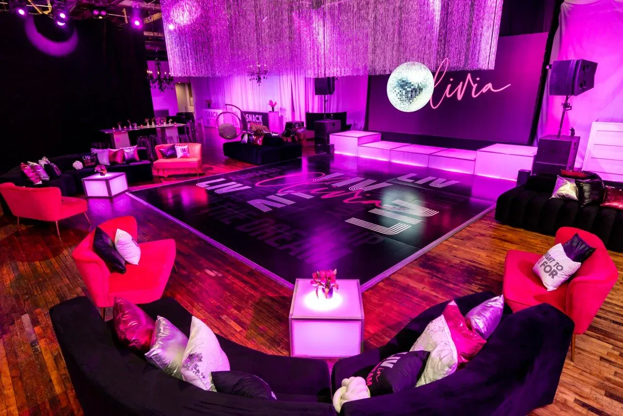 Neon-pink mitzvah dance lounge with a disco ball and custom dance-floor graphics