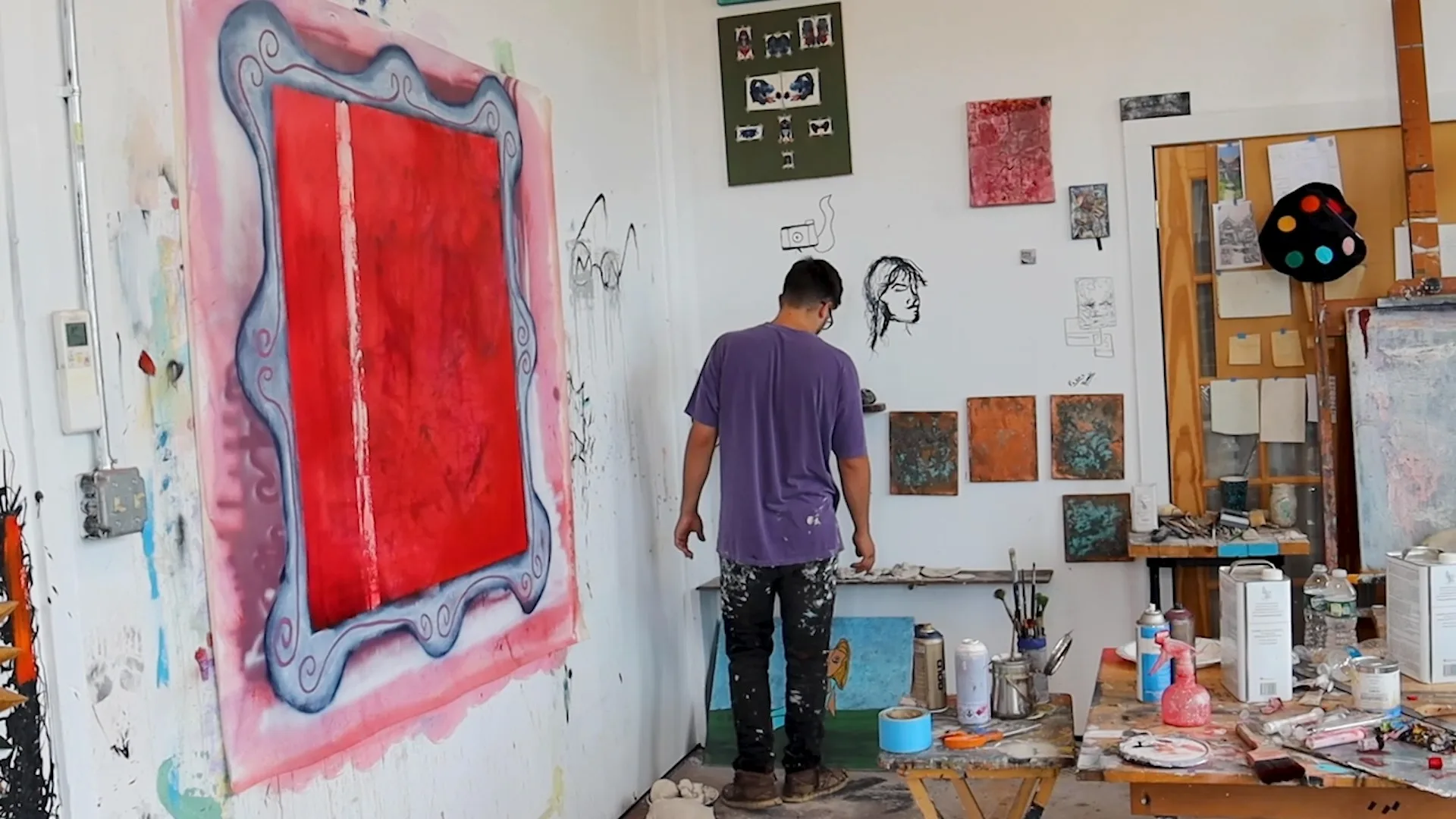 A resident artist at work in their studio at The Knowlton in Bridgeport, CT, surrounded by their own paintings.